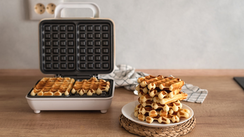 Plate of waffles in front of a waffle iron