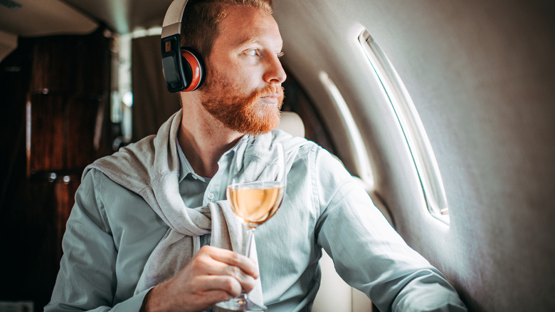 Man holding wine glass in an airplane