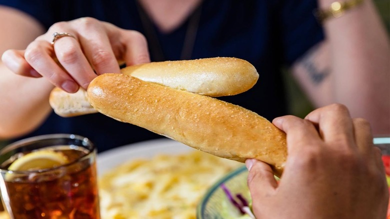 Two diners clink together breadsticks from Olive Garden.