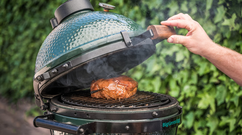 Person grilling meat on barbecue smoker