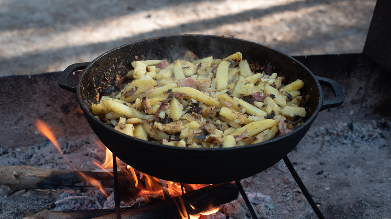 preparing sliced potatoes in a wok outdoors