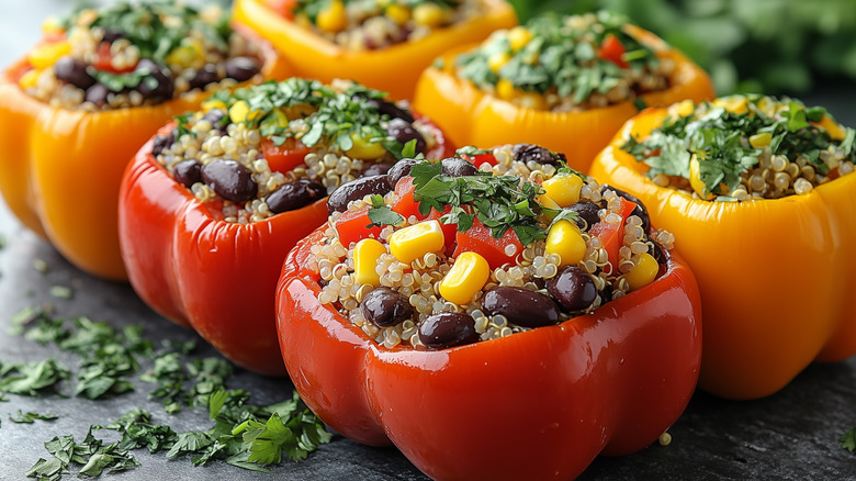 2 rows of red and yellow bell peppers stuffed with quinoa, black beans, corn, and tomatoes