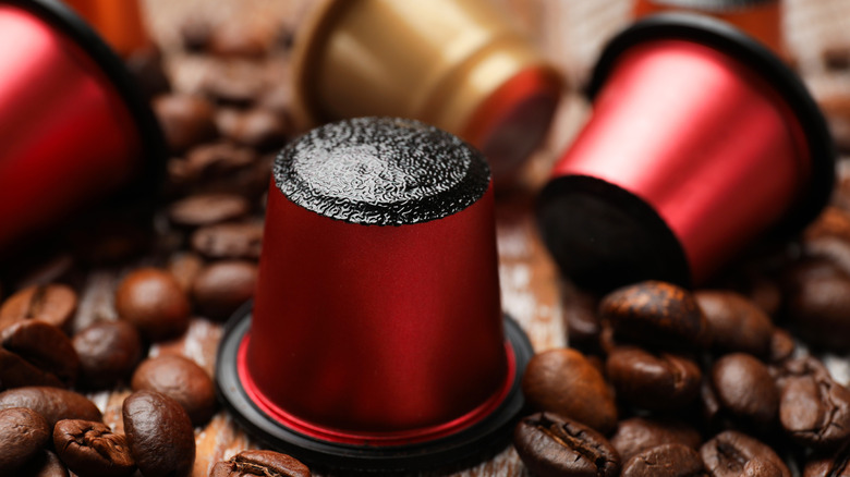 Coffee pods sit on a bed of coffee beans.