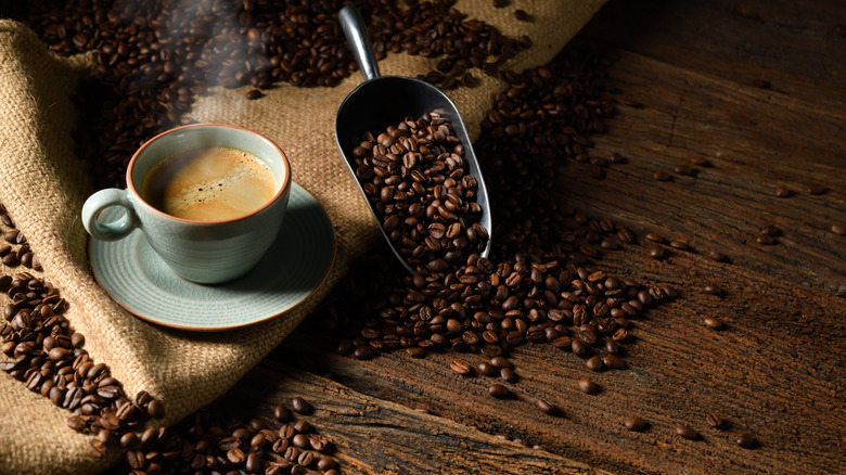 A cup of coffee next to coffee beans