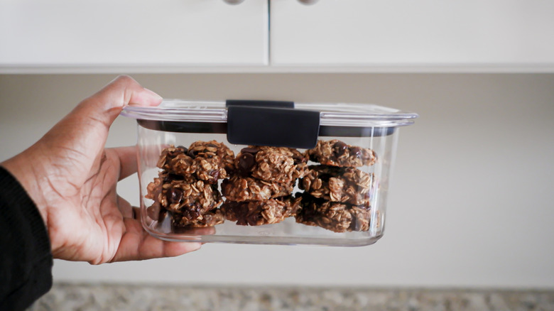 Someone holds an airtight container of oatmeal raisin cookies