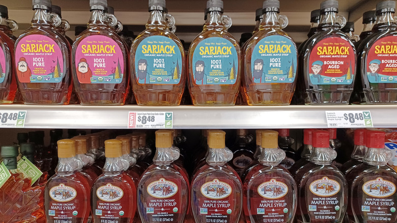 Various maple syrup bottles on a grocery store shelf.