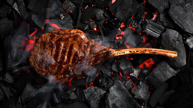 A seared tomahawk steak laid directly onto hot coals
