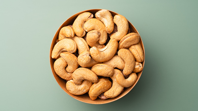 A bowl of cashews on a green background