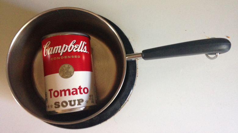 A can of soup sits in a pot.