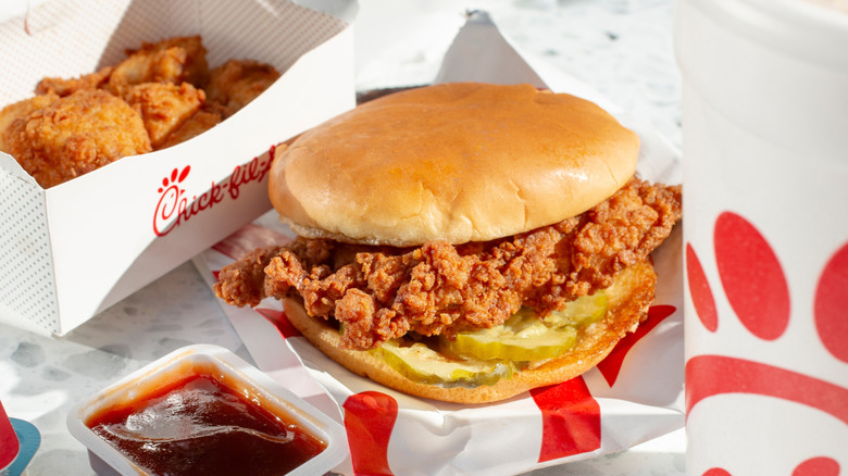 A Chick-fil-A chicken sandwich on a table surrounded by various Chick-fil-A menu offerings