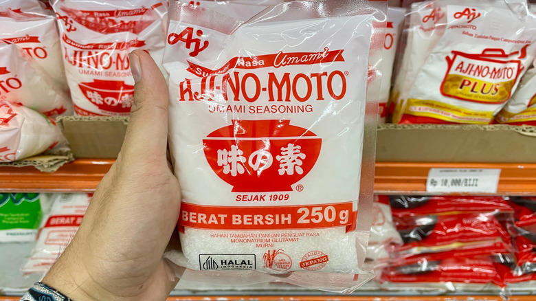 A hand holding a packet of Ajinomoto-brand MSG at the grocery store