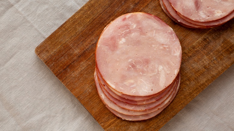 Sliced deli ham sits on a wooden cutting board