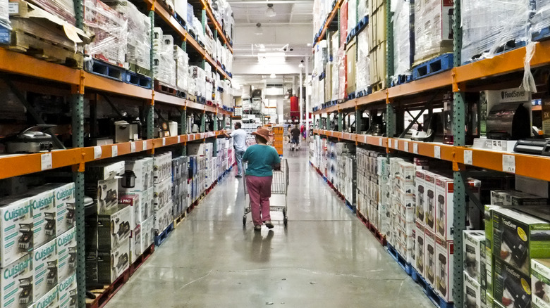 A shopper pushes a shopping cart through an aisle in a Costco store