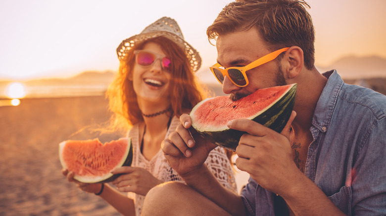 couple eating watermelon on beach