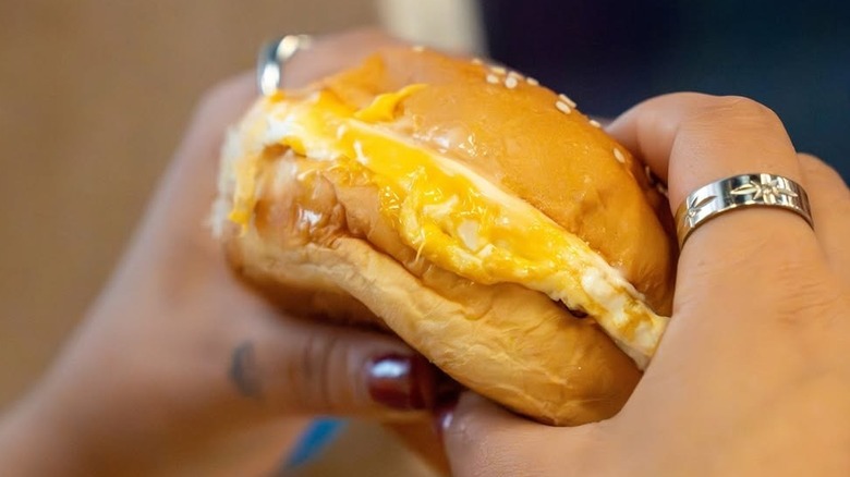 Female hands hold a Five Guys egg and cheese breakfast sandwich