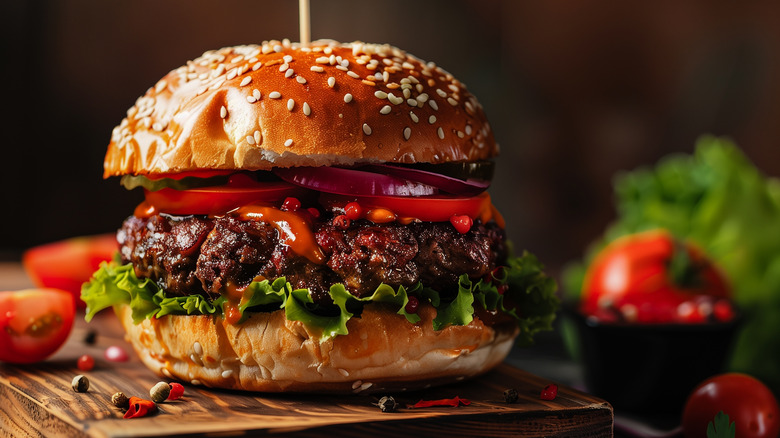 A thick beef burger with ketchup dripping down the sides