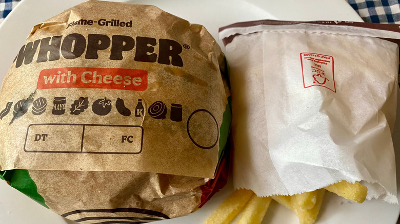 A wrapped Whopper with cheese and a side of fries.
