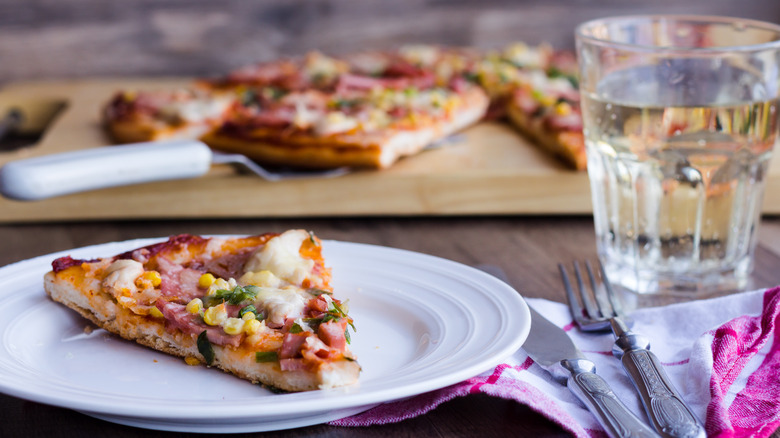 Crispy slice of pizza with glass of water
