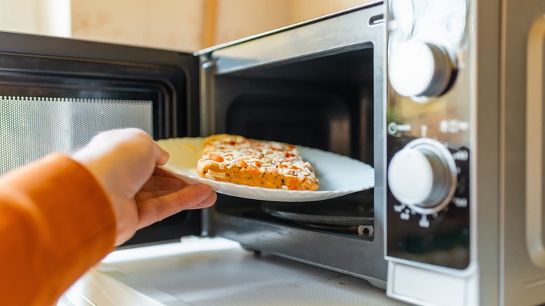 Putting slice of leftover pizza in microwave