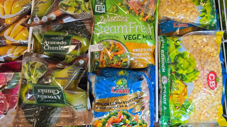Bags of frozen vegetables sit in a freezer in a supermarket