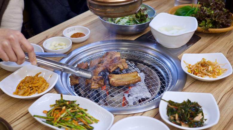 Someone flips meat on a Korean barbecue grill