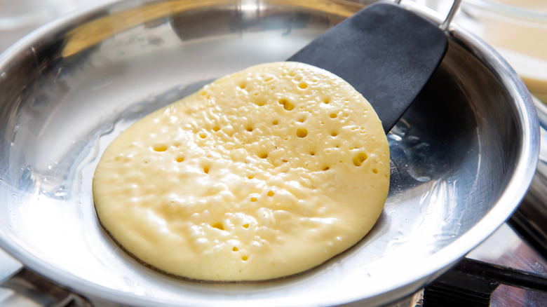 Flipping a pancake in a stainless steel pan.
