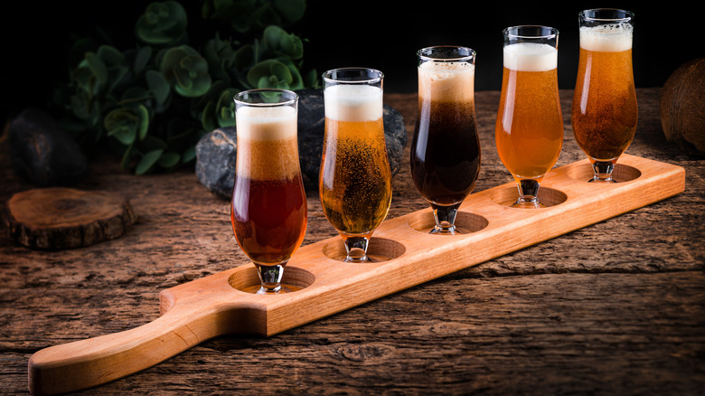 A flight of different beers in a wooden paddle
