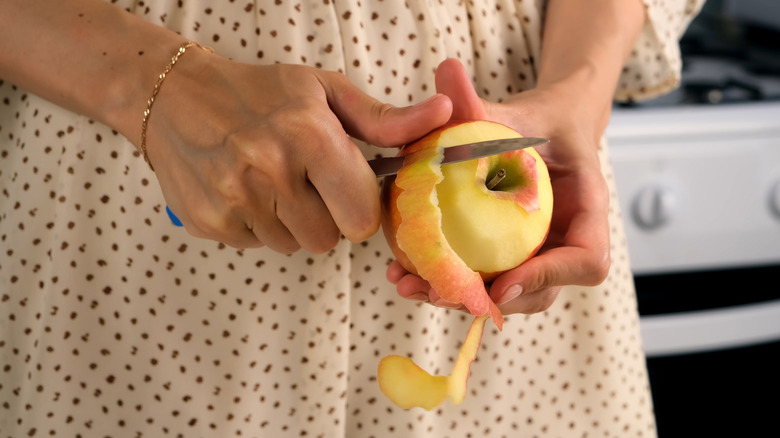 Close up of someone peeling an apple with a paring knife