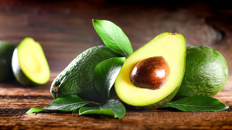 Halved avocados on wood table