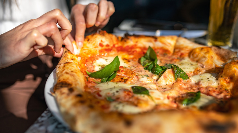 Close up of a diner pulling apart a pizza crust on a margherita pizza
