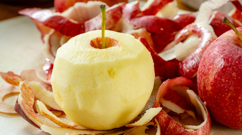a peeled apple surrounded by its skins