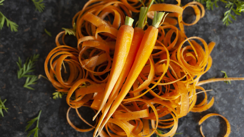 Peeled carrots sitting on top of their skins.