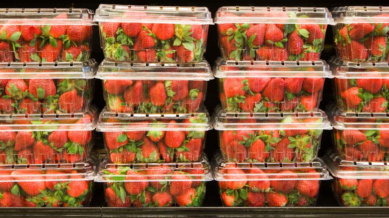 Strawberries in plastic containers on shelves