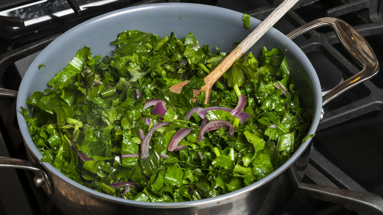 Frying pan full of sautéed kale with red onion