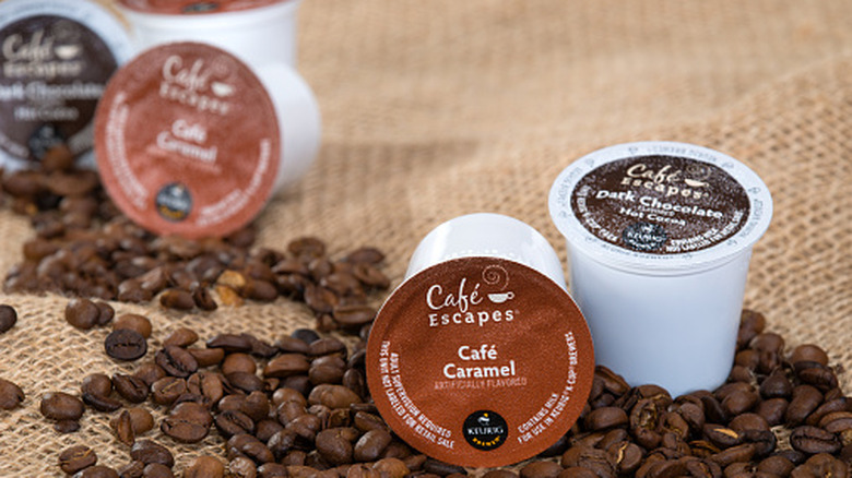 Several k-cups sit among spilled coffee beans.