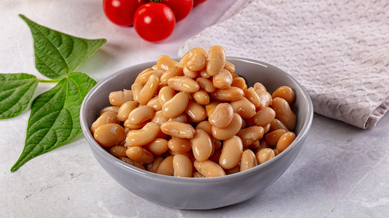 a bowl of canned white kidney beans sits next to a tea towel