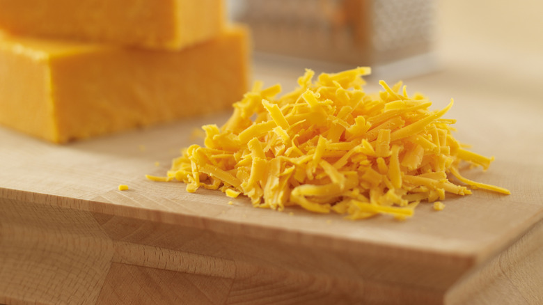 Freshly shredded cheese on cutting board