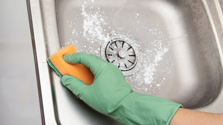 Hand scrubbing kitchen sink with baking soda
