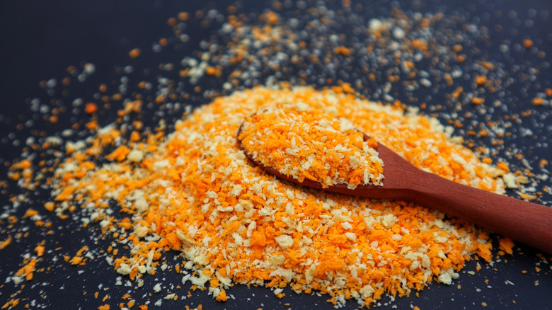 Wooden spoon full of breadcrumbs laying on pile of breadcrumbs