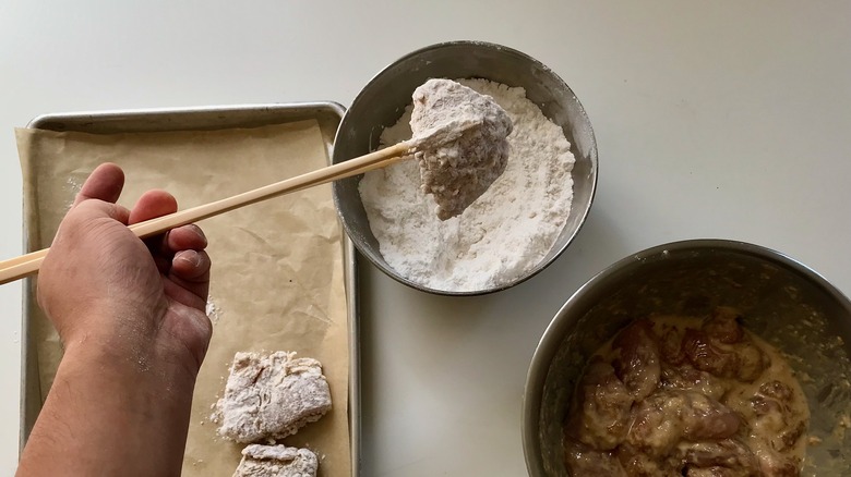 dipping raw chicken in flour