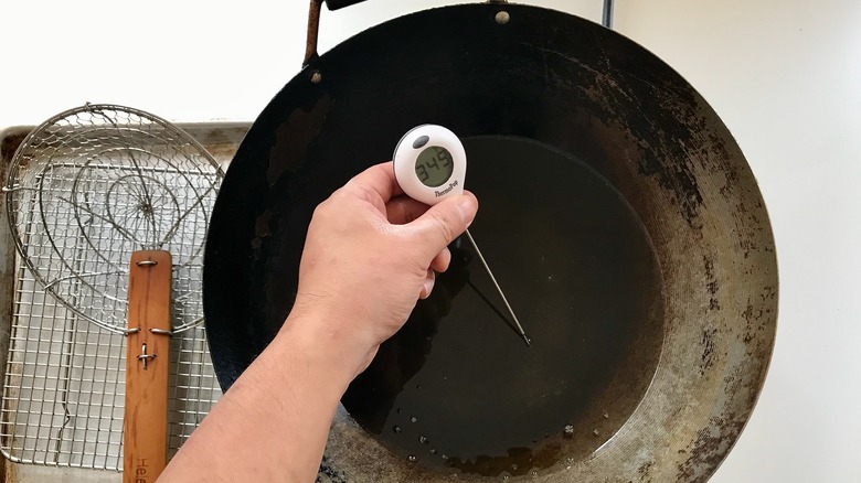 hand holding thermometer in oil