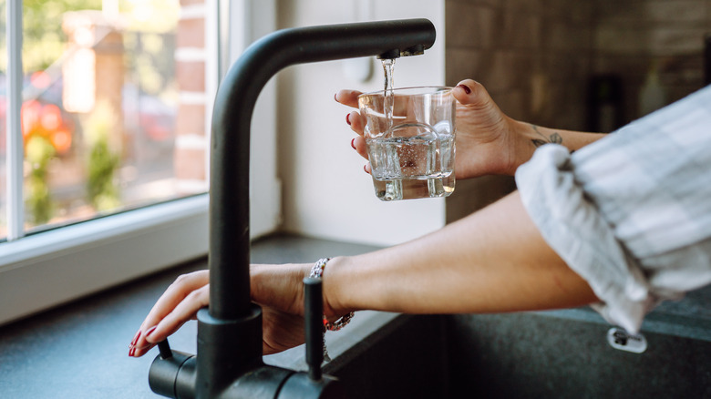 Someone getting water from their sink for drinking