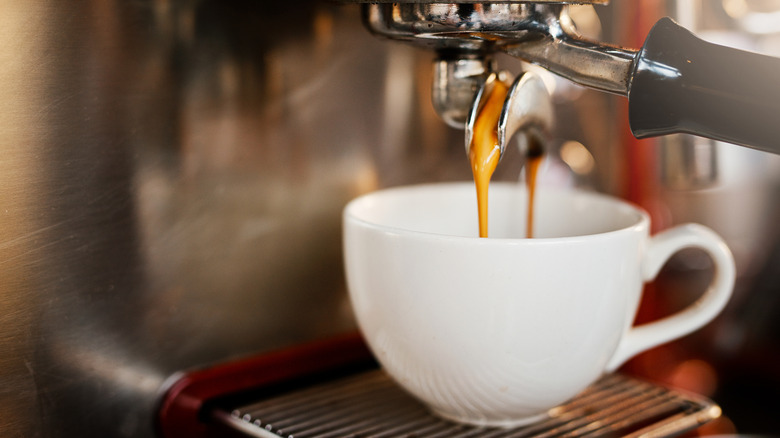 Espresso being brewed into a white coffee cup.