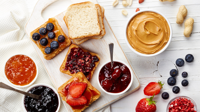 Various breads, jellies, and peanut butter on a table
