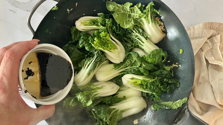 pouring sauce over bok choy