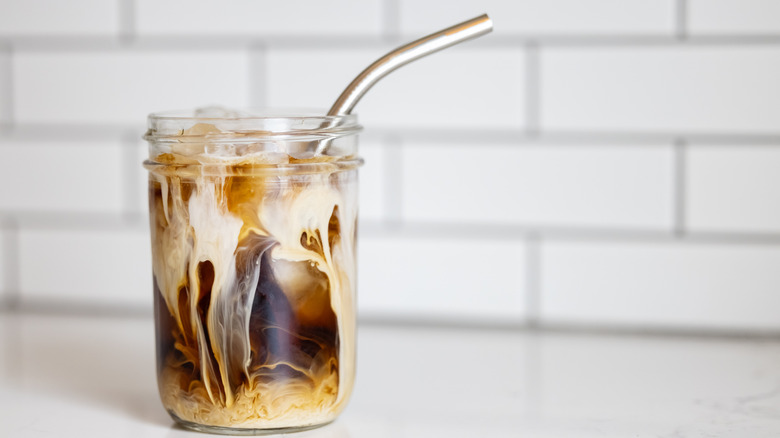 Cold brew and creamer in a glass with a straw