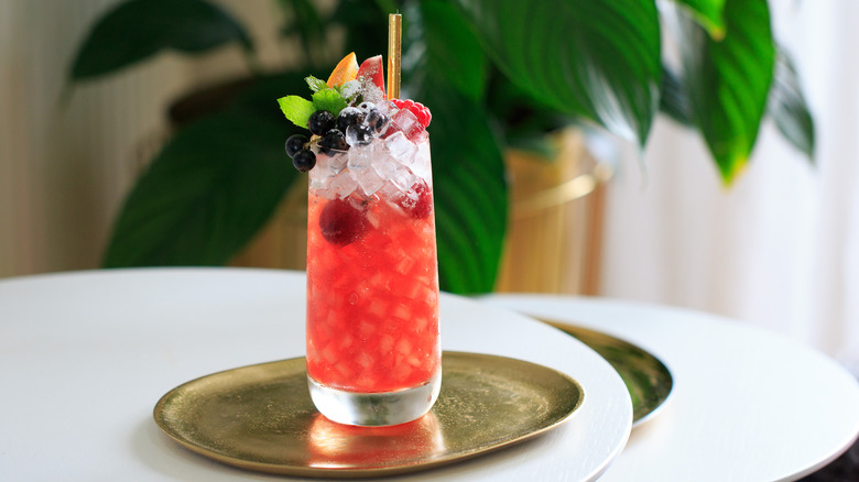 Tropical red drink with pebble ice and fruit