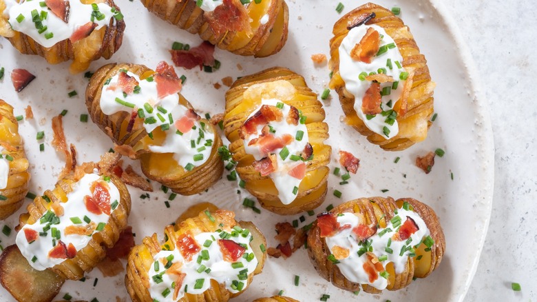 Hasselback potatoes topped with cheese, bacon, and sour cream