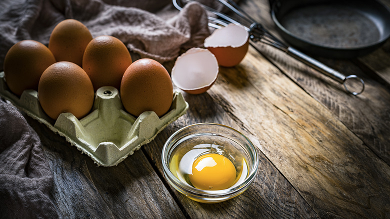 A dozen whole eggs and one cracked egg on counter