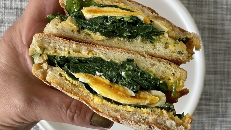 hand holding spinach egg sandwich